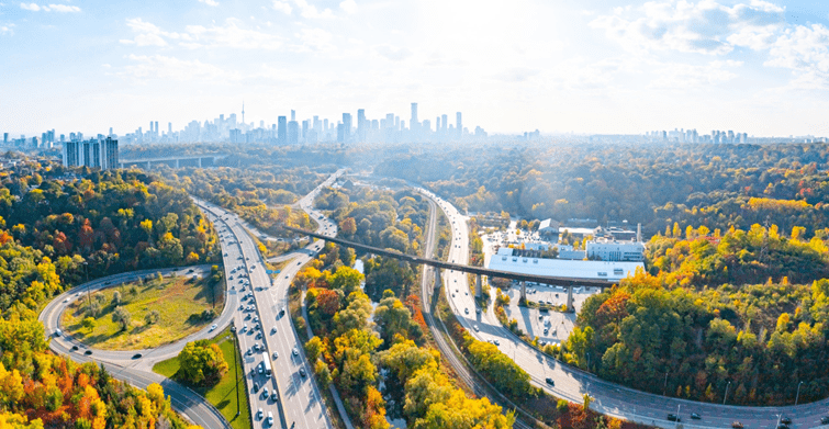 Aerial view of Toronto city skyline during autumn, showcasing vibrant foliage and bustling traffic.