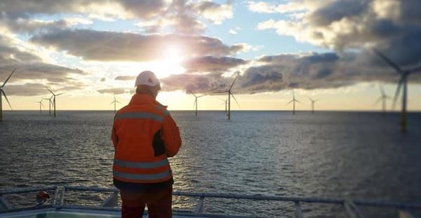 Arcadis leads planning for Rhein-Main-Link energy route Offshore manual worker standing on helipad with wind-turbines behind him in sunset