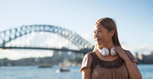 Combatting air pollution in and around Sydney Woman in Sydney wearing headphones with Sydney Harbour Bridge in the background.