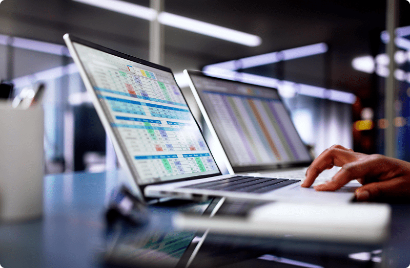 A person typing on a laptop displaying financial data on the screen, focused on their work.