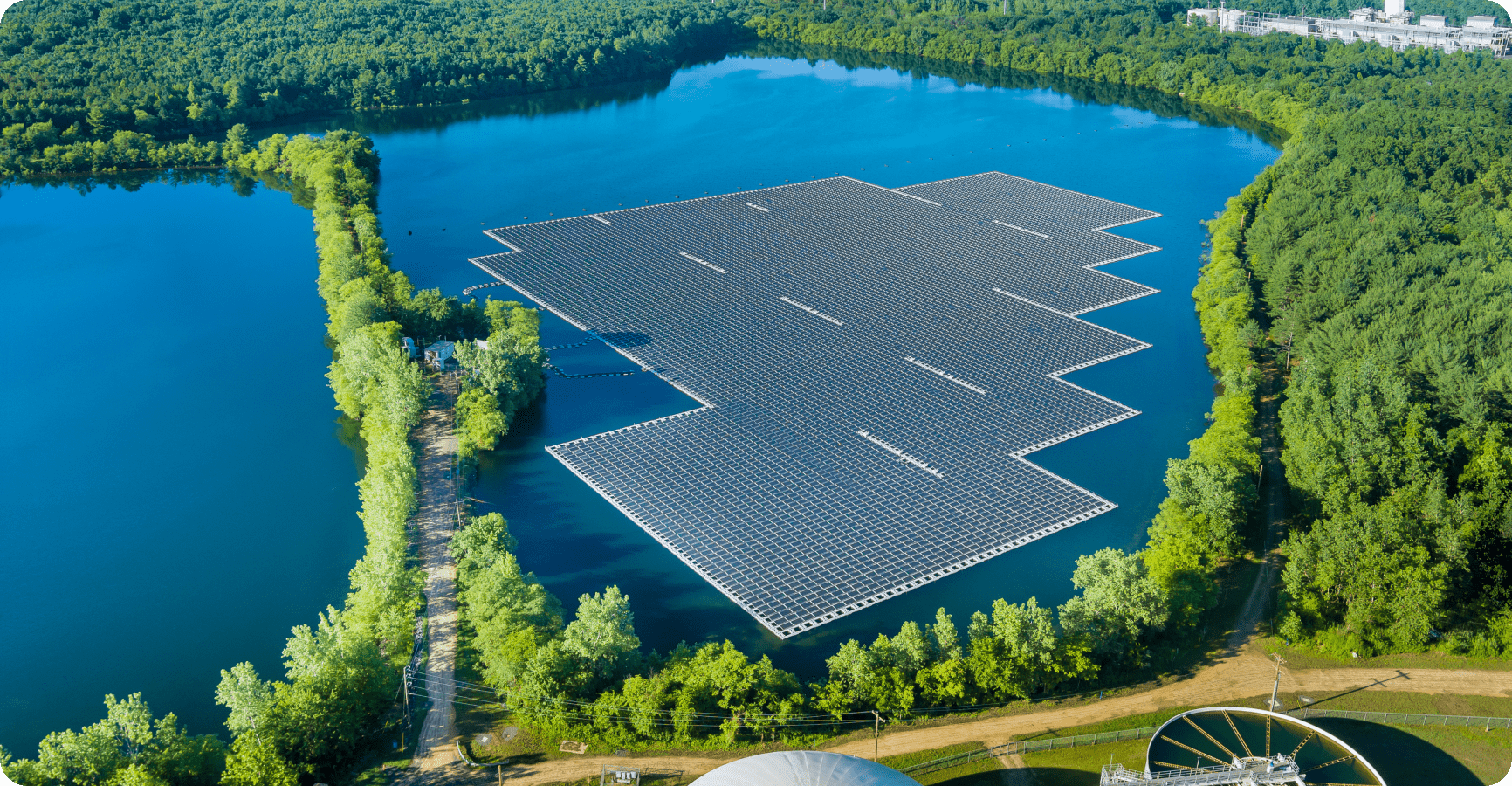 A vast solar panel installation rests on a tranquil lake, encircled by verdant trees, highlighting sustainable energy solutions.