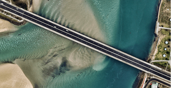 Overhead shot of a bridge over a flowing river, showcasing the architectural structure.