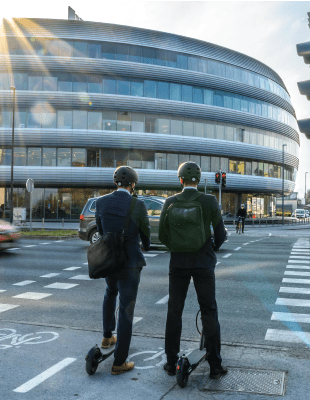 Two people waiting at a crossroads on e scooter