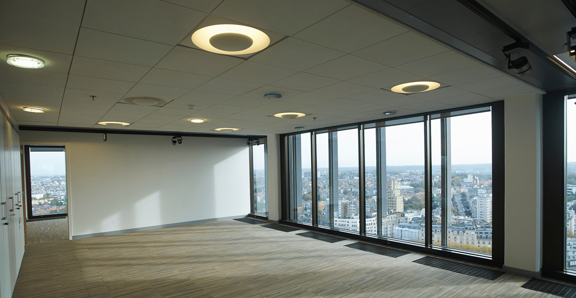 Empty office space with floor‑to‑ceiling windows and city view.