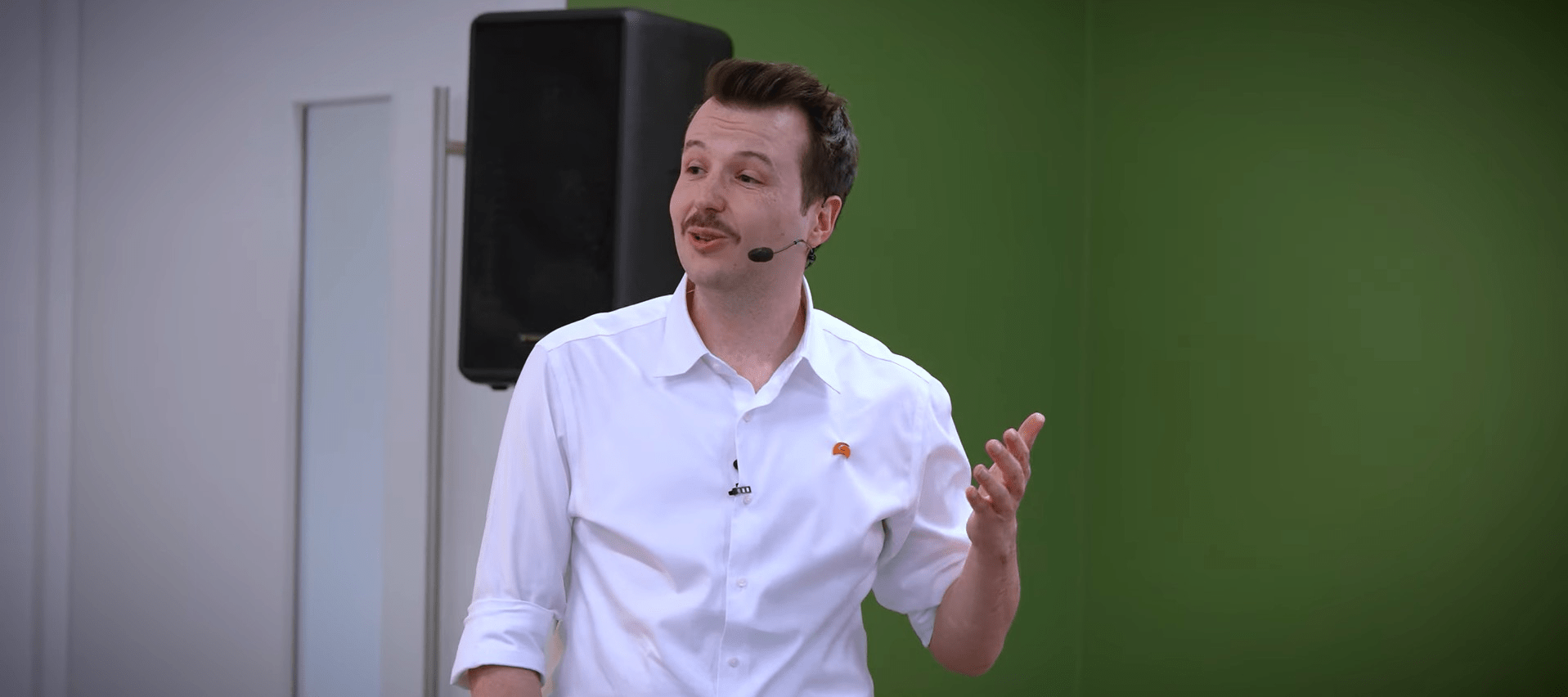A man presenting in front of a large screen, engaging the audience with visual aids and clear communication.