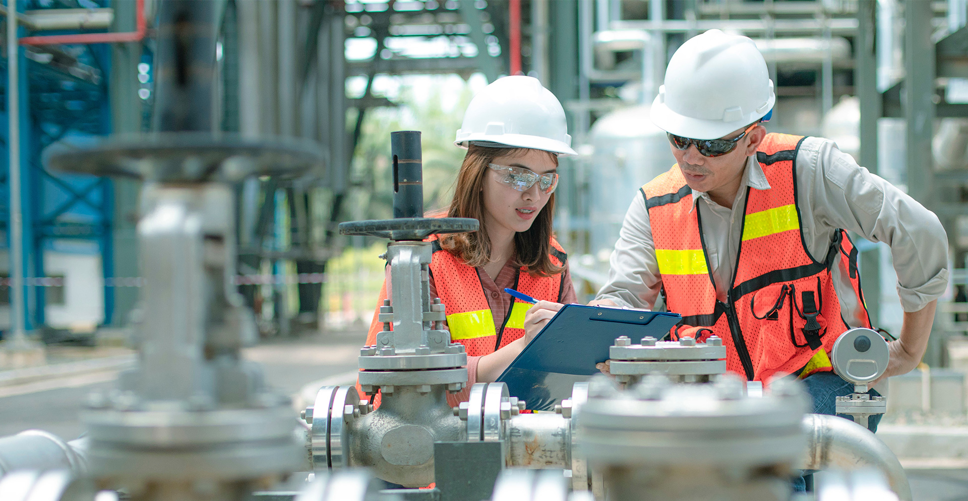 Industrie, fabriekscomplex met twee mensen die iets bespreken vanaf een clipboard.