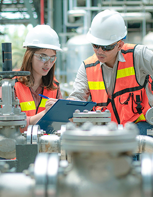 Industrie, fabriekscomplex met twee mensen die iets bespreken vanaf een clipboard.