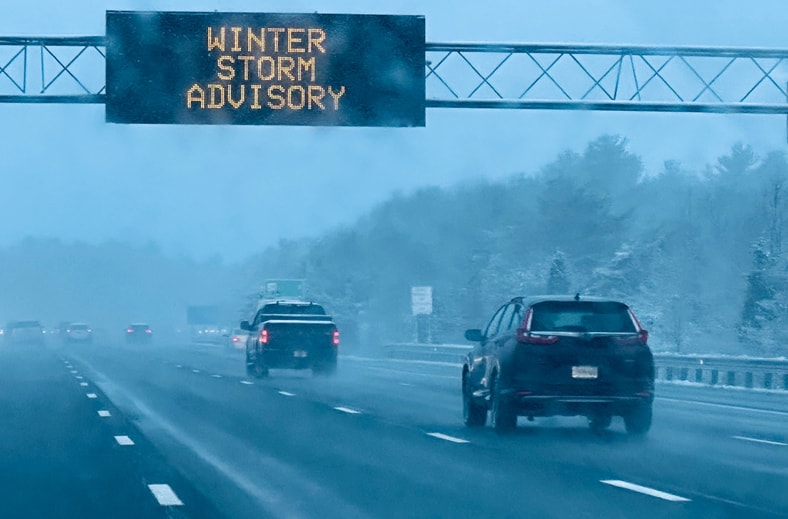 An image of a snow-covered road with a "Winter Weather Advisory" notice and vehicles.