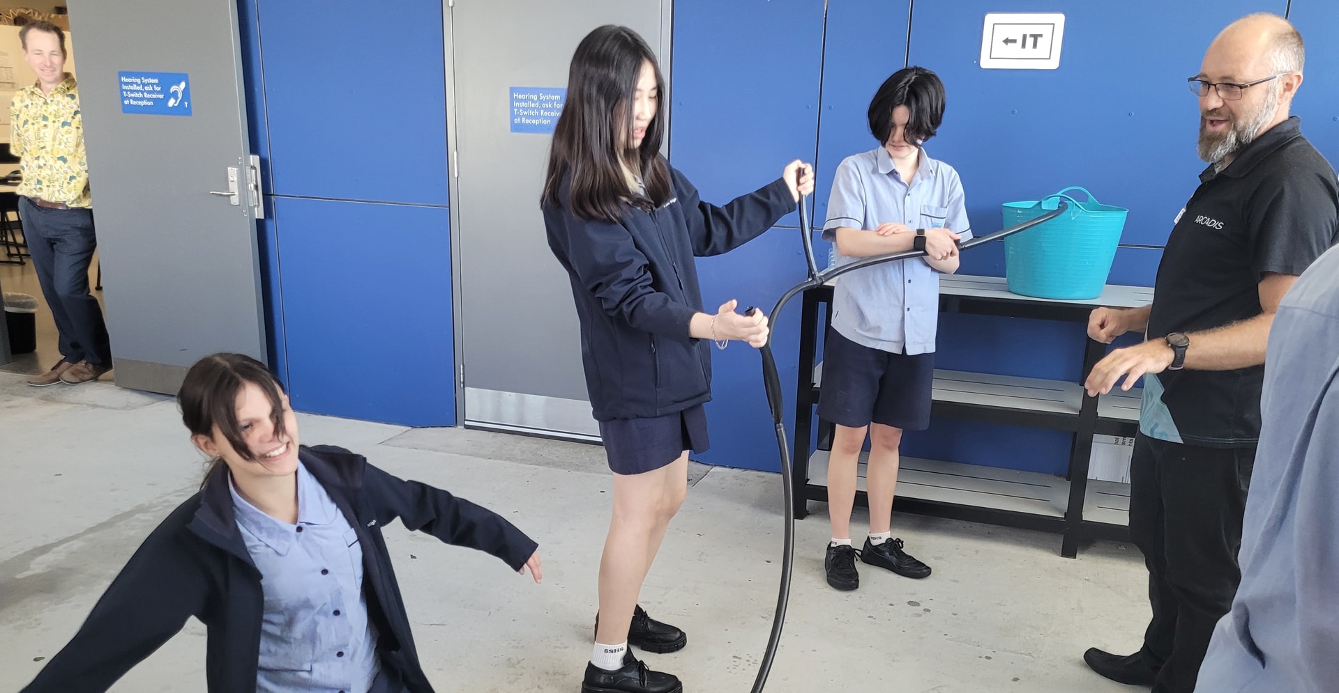 A group of people gathered around a black hose, possibly having an activity.