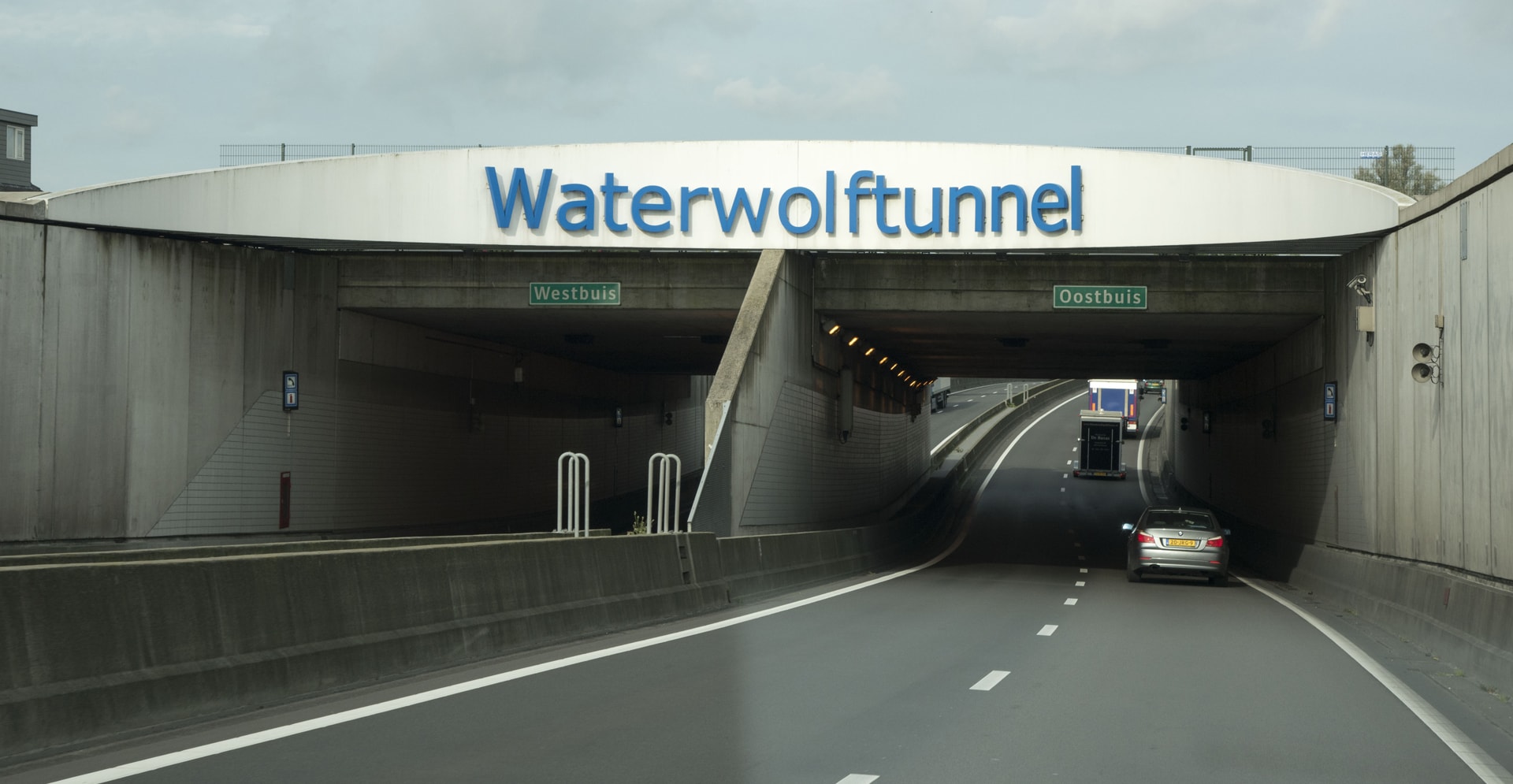 Entrance to the Waterwolftunnel with separate lanes labeled Westbuis and Oostbuis, showing cars entering the tunnel.