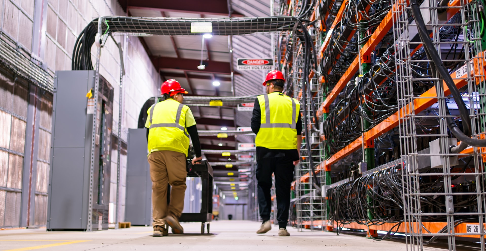 Rear View of Two Technicians Walking Away from the Camera Through Data Center