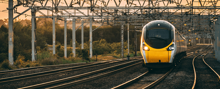 A train traveling along the tracks, showcasing its sleek design against a backdrop of greenery.