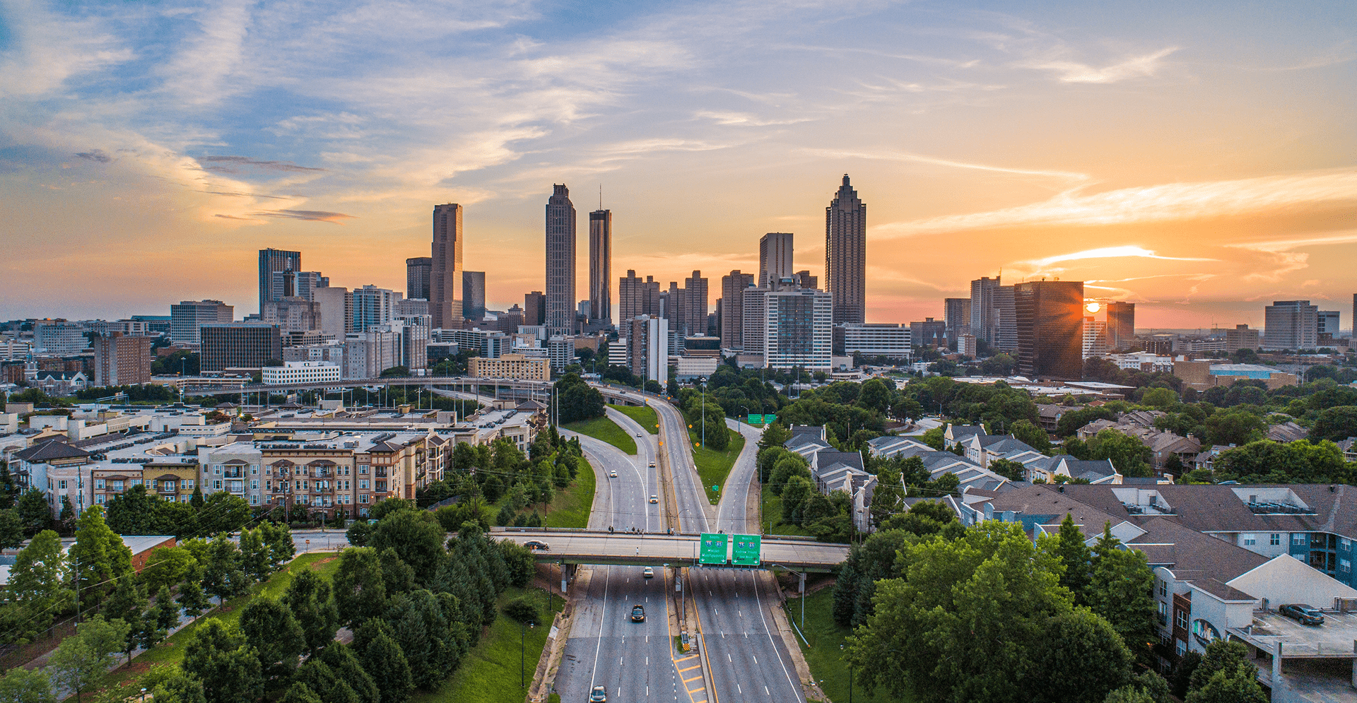 Urban skyline with skyscrapers, a busy highway, and a road weaving through the city landscape during daylight.