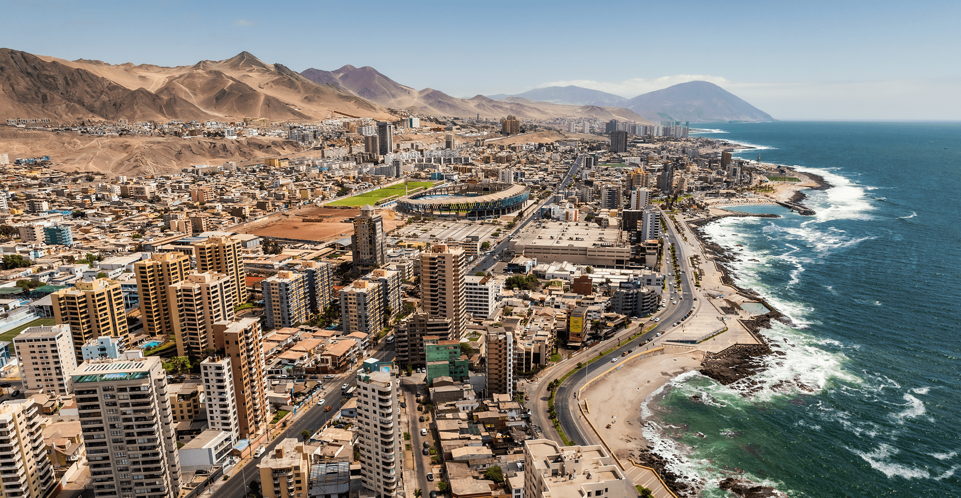 A city skyline with mountains and the ocean visible in the background, showcasing a scenic urban landscape.
