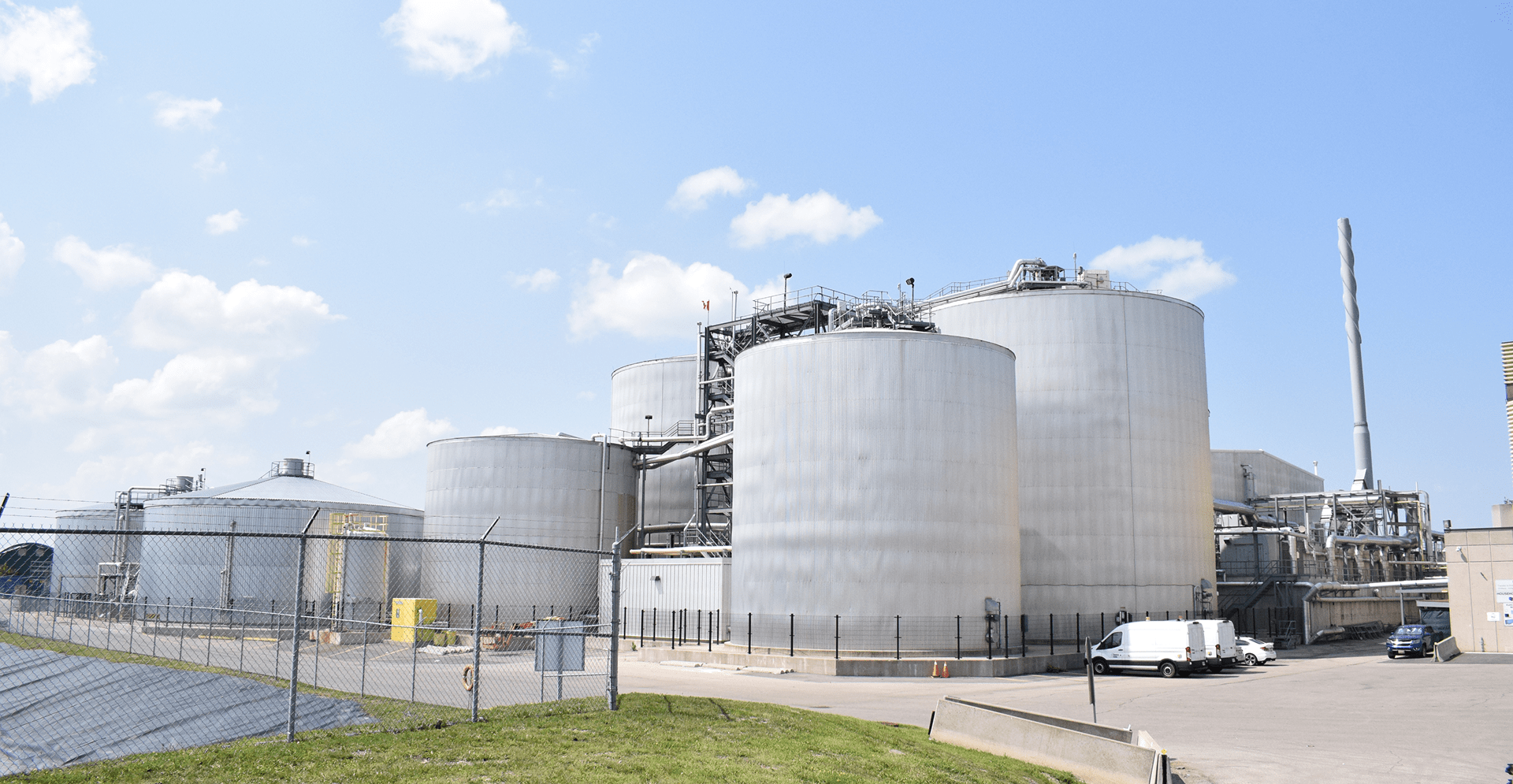 A large industrial plant featuring multiple tanks surrounded by a security fence.