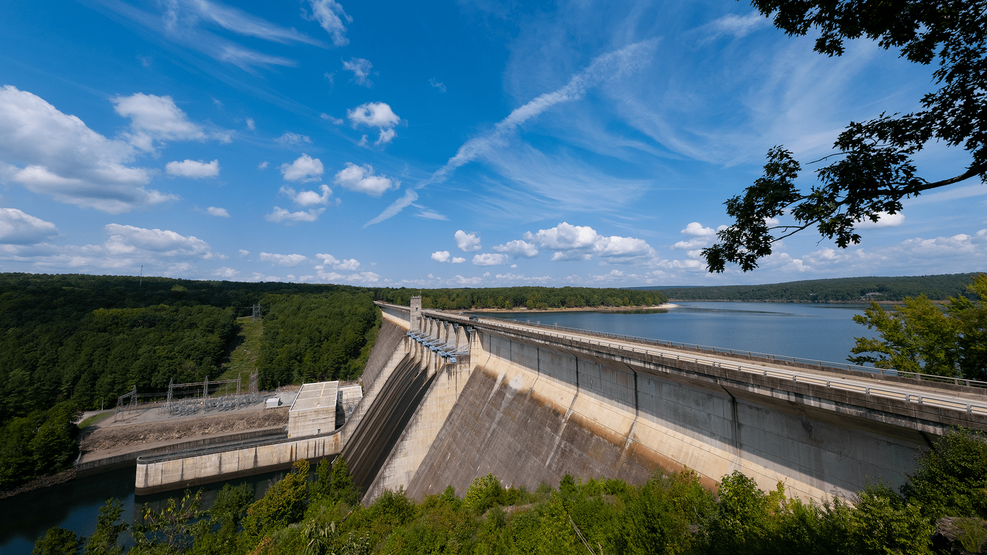 A large dam stands over a vast body of water, showcasing its impressive structure and surrounding landscape.