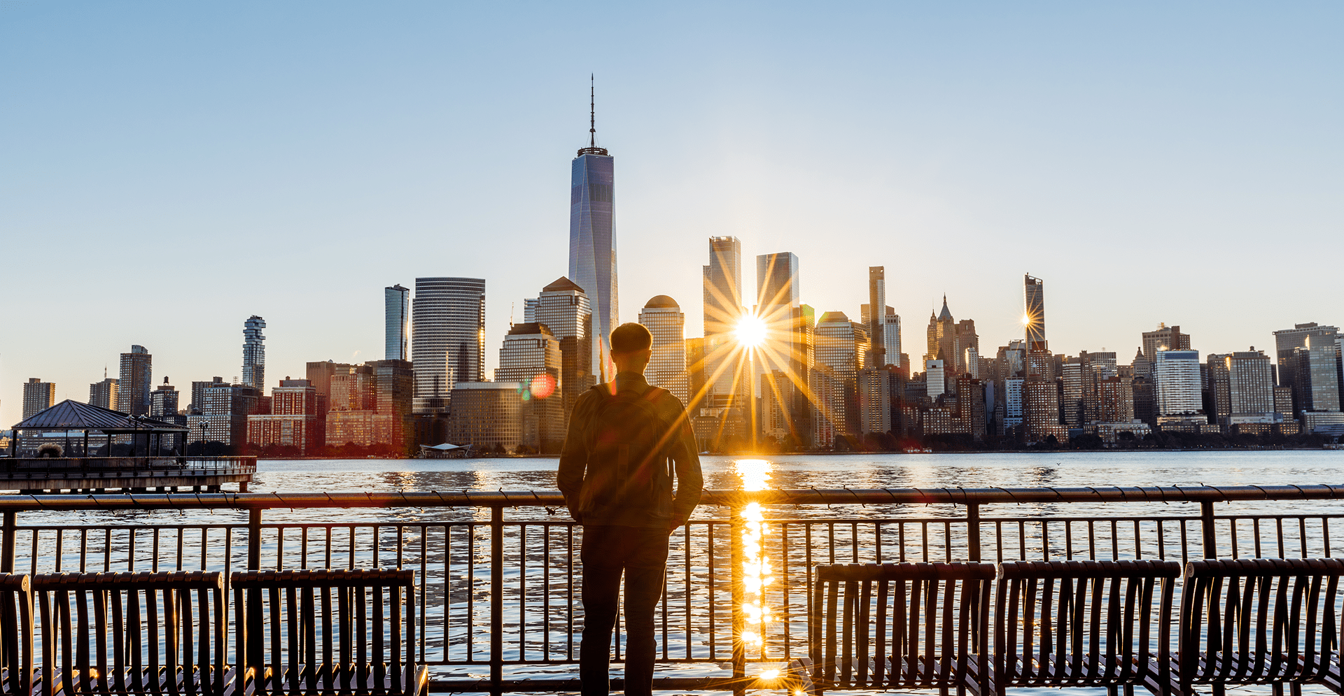 Rear view of a man looking at New York City skyline at sunrise, USA