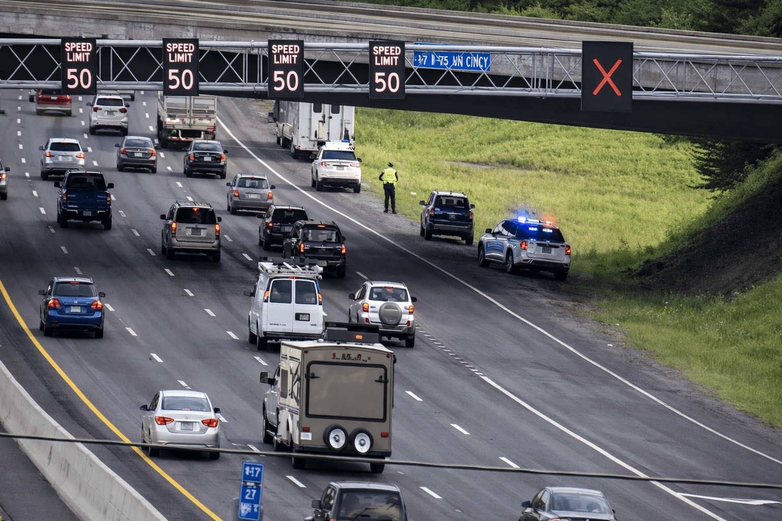 Traffic flows smoothly beneath a concrete overpass on a busy highway, with vehicles moving in both directions.