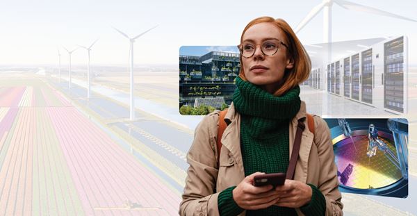 A woman in a cozy sweater is seen holding a cell phone, with wind turbines in the backdrop, representing sustainable energy sources.