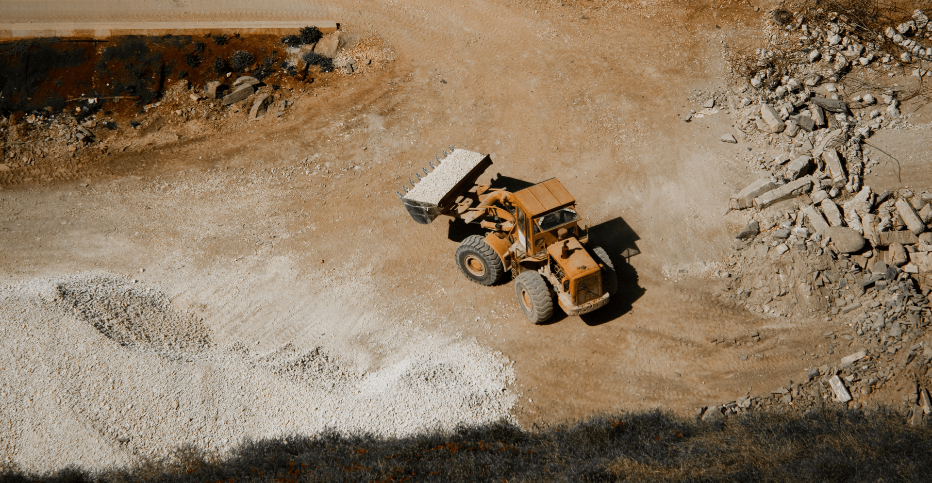 Ein großer gelber Muldenkipper fährt auf einer Schotterstraße.