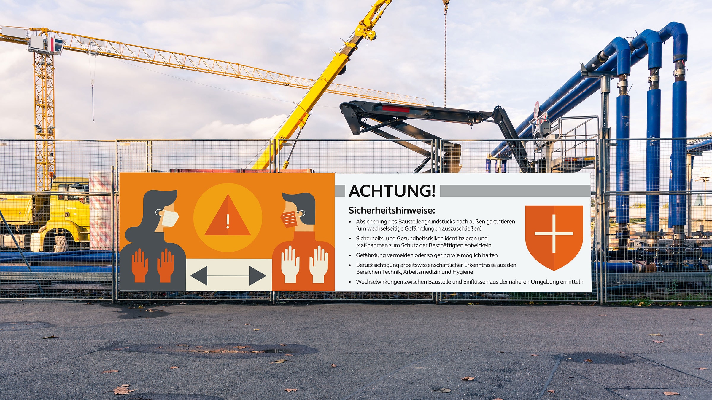 Schild mit Sicherheitshinweisen an Baustellenzaun mit Kran im Hintergrund