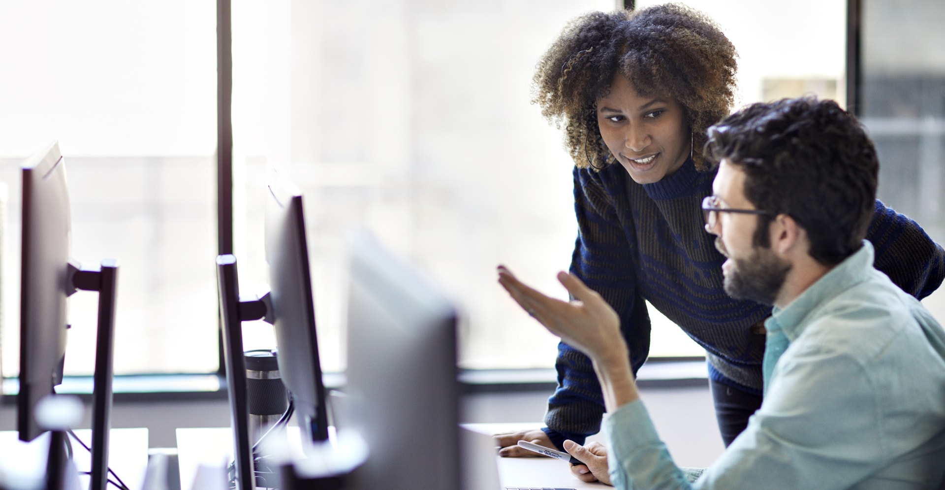 A man and woman discussing in front of computer