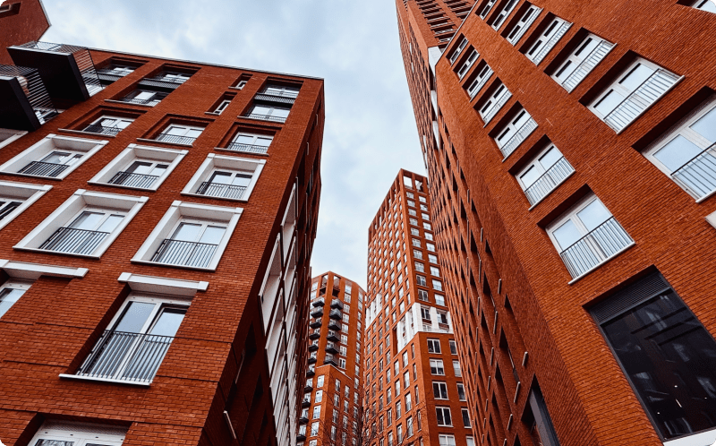 Red brick buildings line a city street, showcasing urban architecture against a clear blue sky.