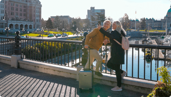 Mature couple takes selfie, British Columbia Legislative building in distance