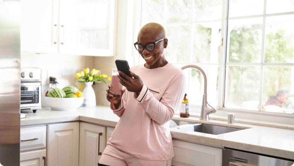 A woman in a pink shirt engrossed in her cell phone, focusing on the screen with intense concentration.