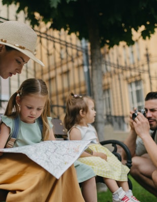 A family sits on a bench, examining a map together, discussing their next destination.