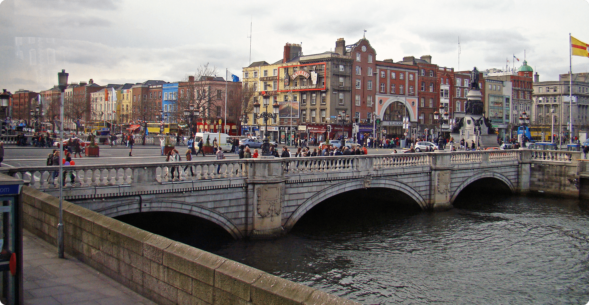 A scenic bridge spans a river, connecting two banks under a clear blue sky.