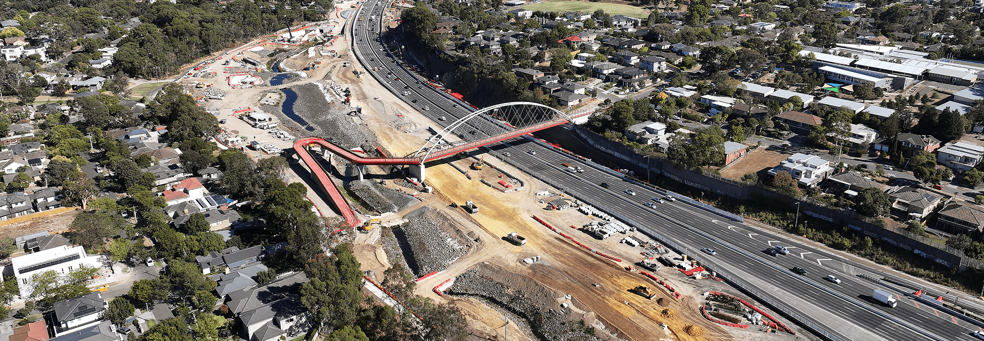Aerial view of a freeway construction site, showcasing machinery and workers on the developing roadway.