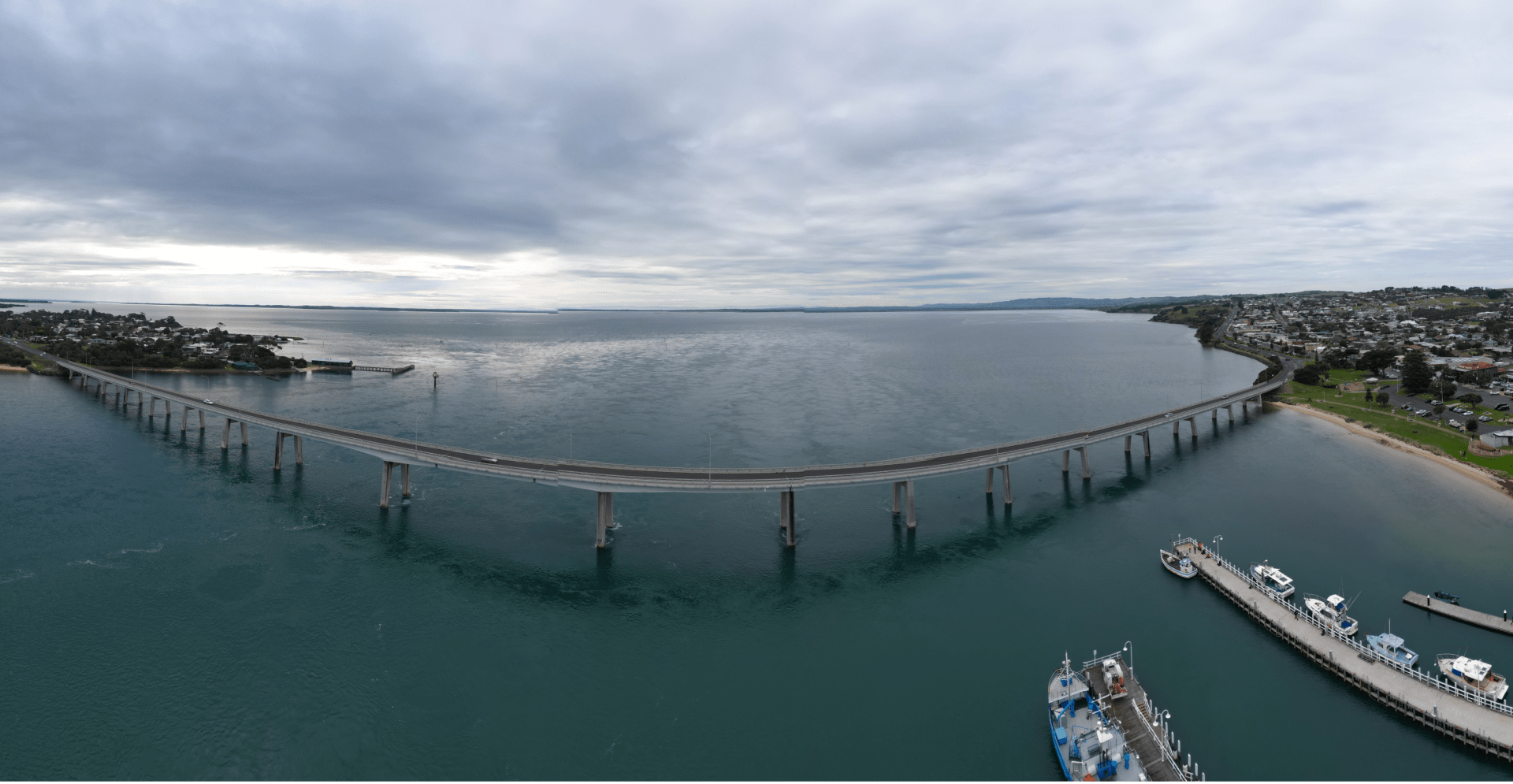 A bridge over water with distant boats.