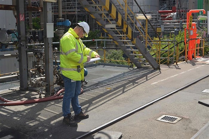 Mann in Schutzausrüstung führt Prüfung durch auf einer Baustelle