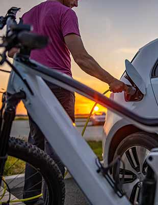 Mann steckt elektrischen Stecker in Auto zum Aufladen Mann steckt elektrischen Stecker in Auto zum Aufladen