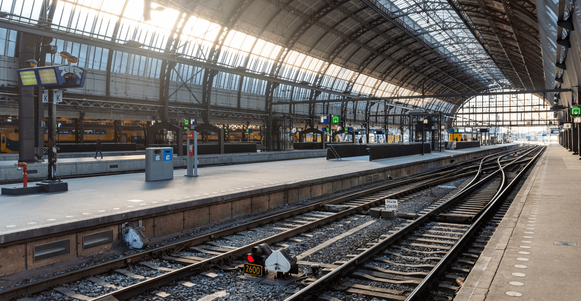 A train station featuring a train on the tracks, surrounded by platforms and waiting passengers.
