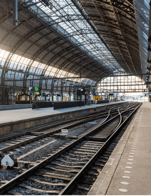 A train station featuring a train on the tracks, surrounded by platforms and waiting passengers.