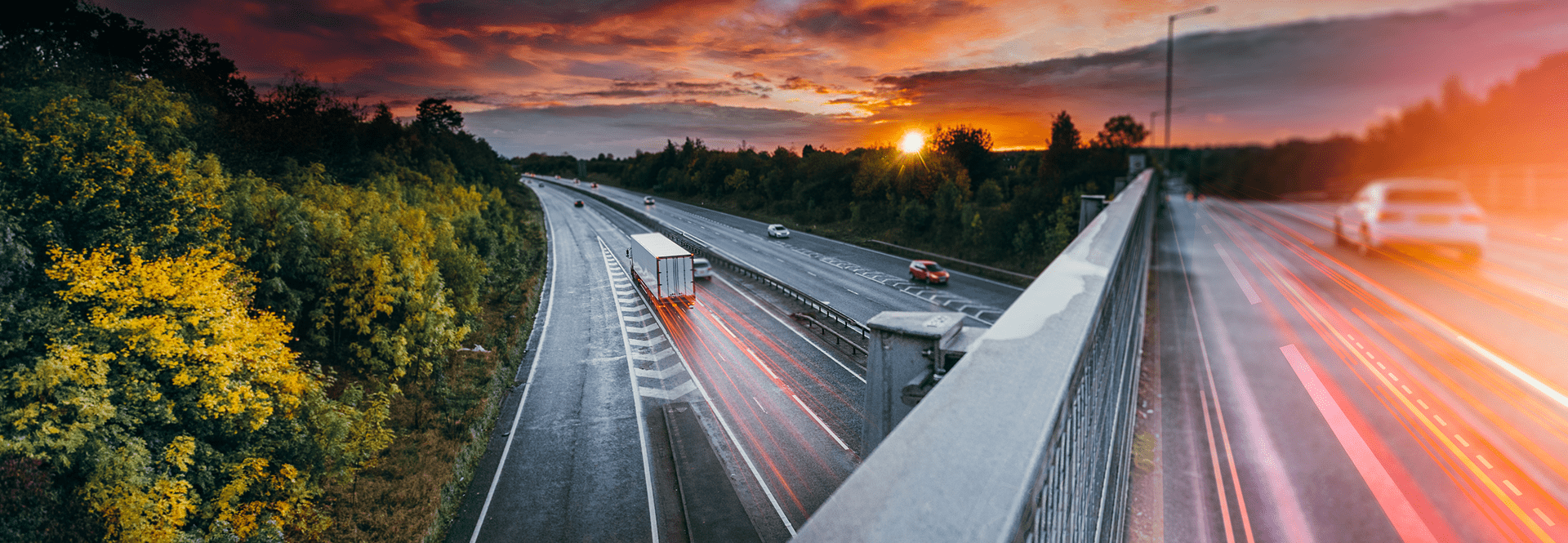 Sunset over a highway, showcasing cars in motion against a backdrop of warm, glowing hues.